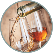 2A20EPP Dispensing golden sherry, a speciality from Andalusia, Spain, into wineglasses in a close up on the neck of the bottle over wood with copy space